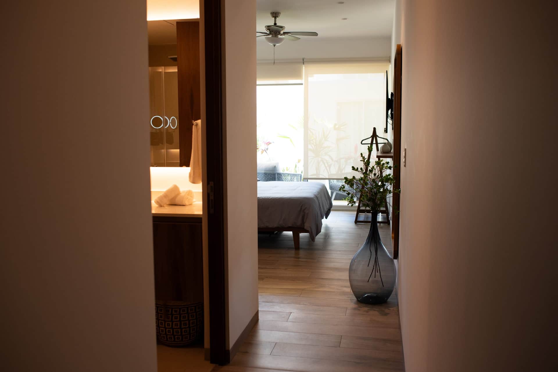 Primary suite bedroom with ensuite bathroom and tropical light at The Leaf Playacar