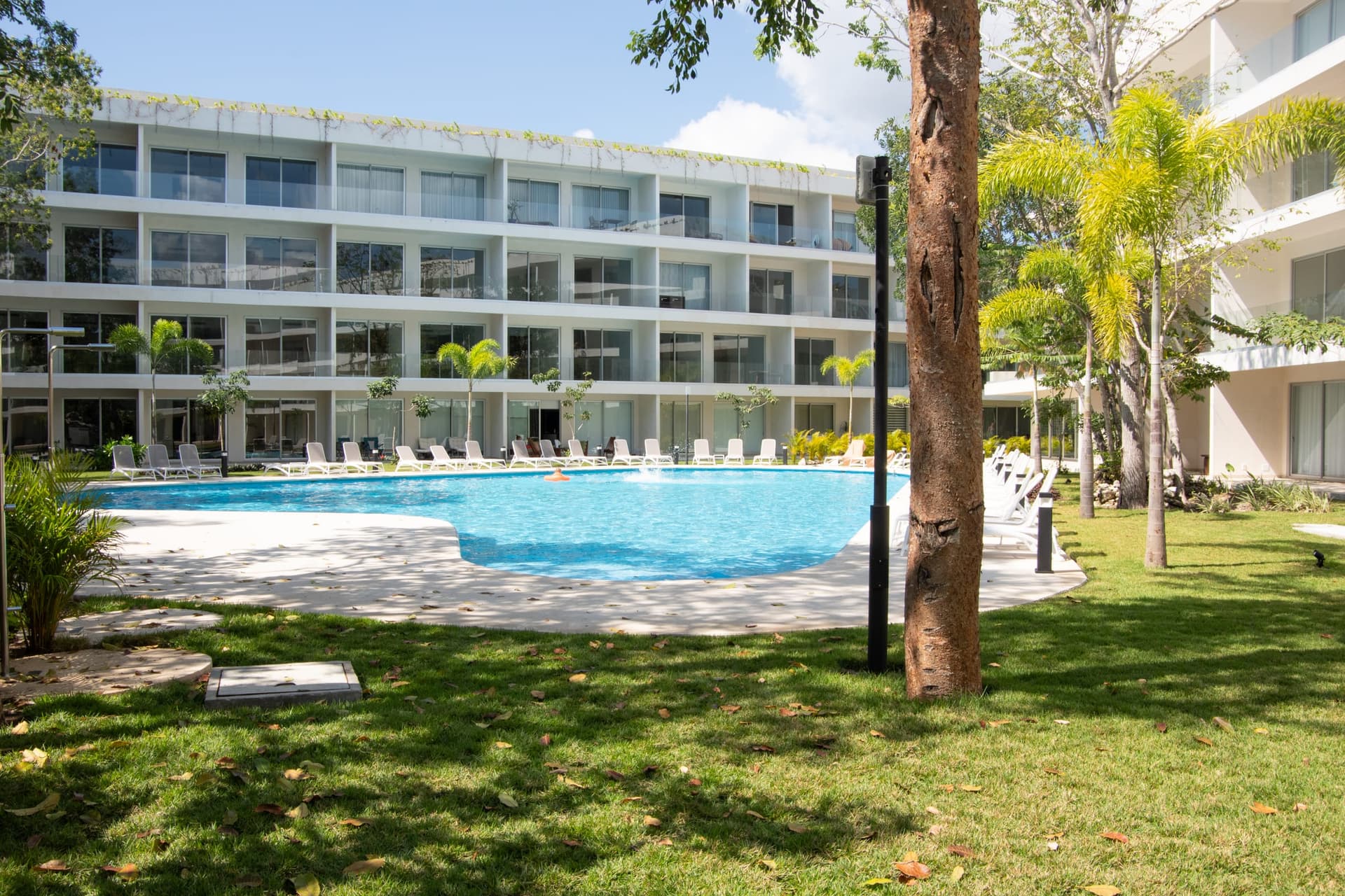 Resort-style community swimming pool with lounge chairs at The Leaf Playacar