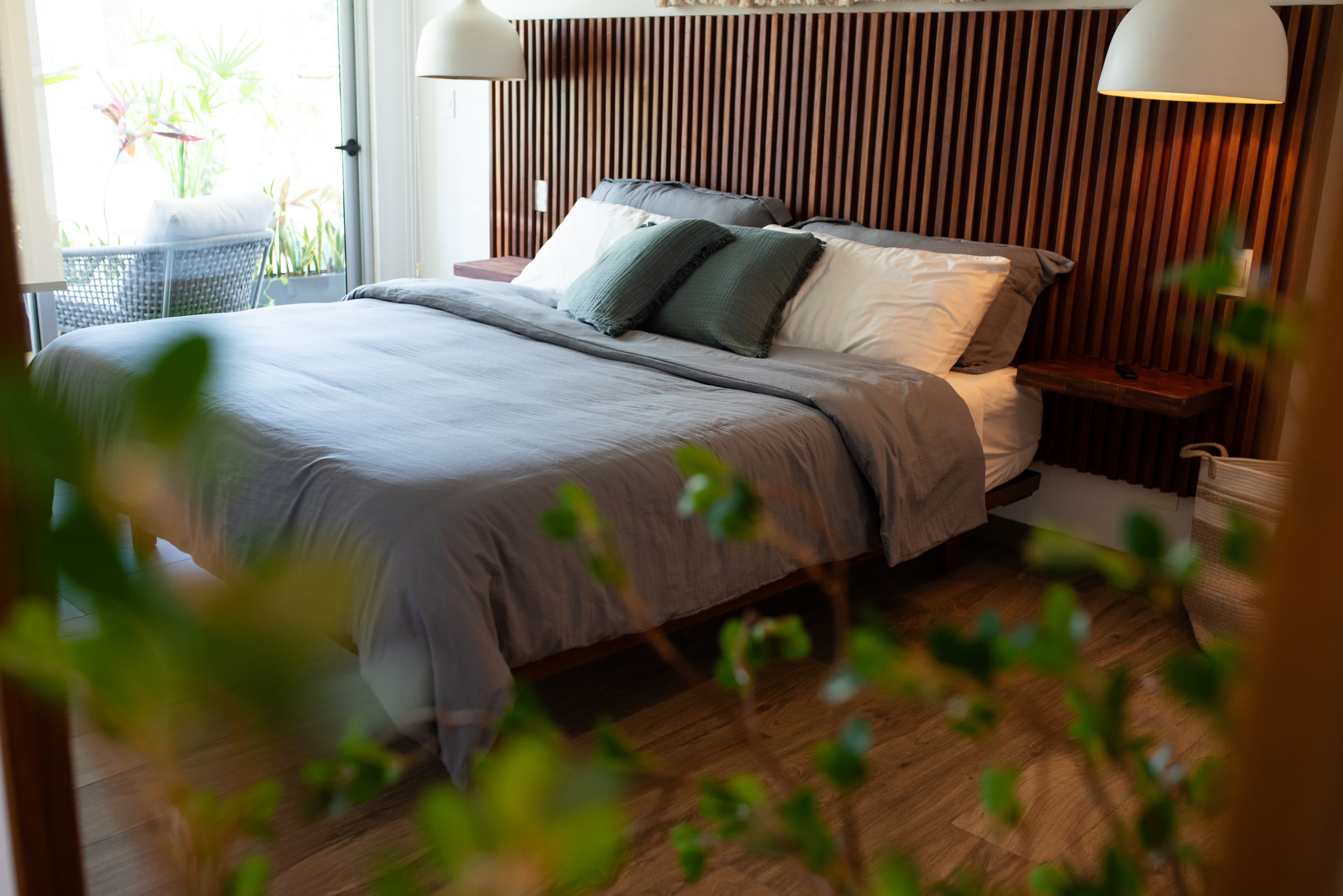 Restful bedroom with macrame wall hanging, woven pendant light, and built-in wardrobes at The Leaf Playacar